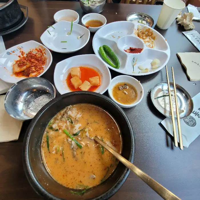 테이블에 차려진 푸짐한 한 상차림, 순대국밥과 다양한 밑반찬들