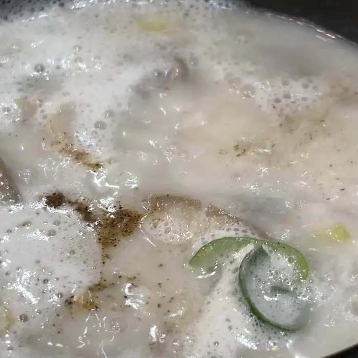 순대국밥 국물의 클로즈업, 뽀얗고 진한 국물과 후추, 파 등이 보이는 모습