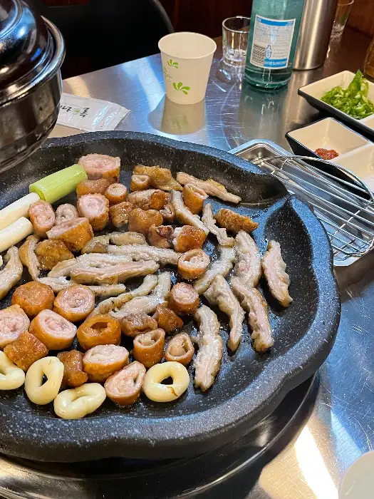 다양한 종류의 막창과 구운 채소가 철판에 놓여 있는 모습