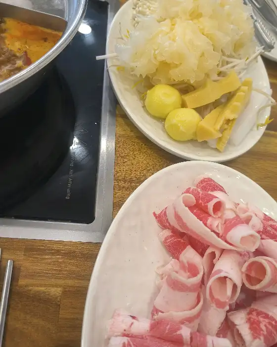 훠궈 냄비 옆에 놓인 신선한 고기 롤과 야채 플레이트