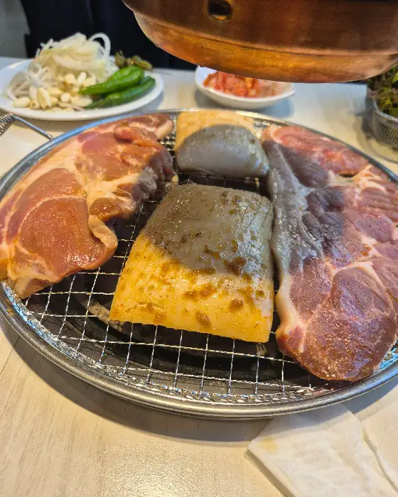 숯불 위에서 맛있게 익어가는 삼겹살과 다른 고기들