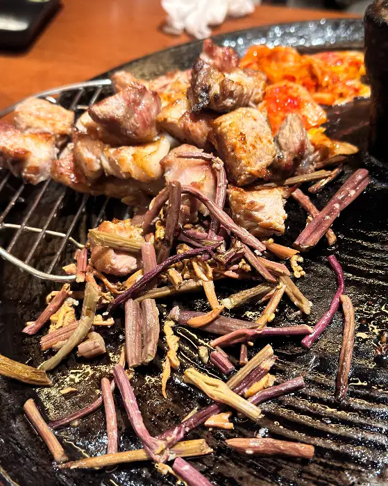 잘 익은 삼겹살 조각과 곁들임 야채
