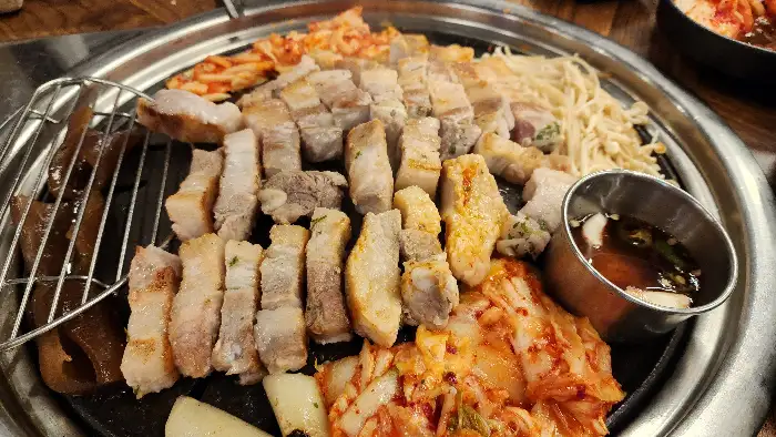 불판 위에 올라간 삼겹살과 김치, 팽이버섯