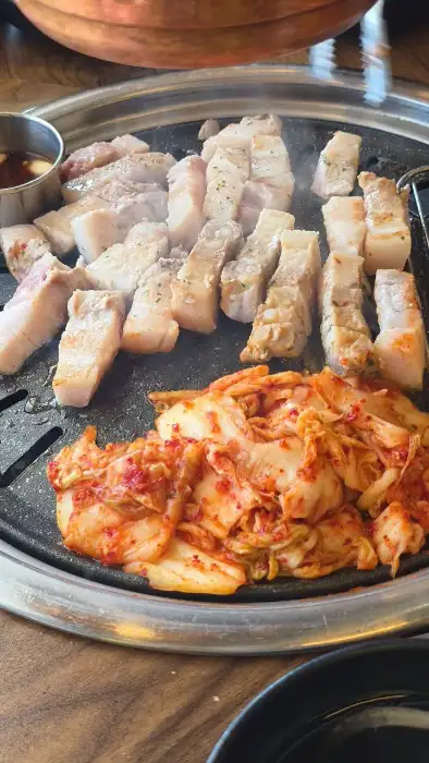 잘 구워진 삼겹살 조각들과 곁들임 음식