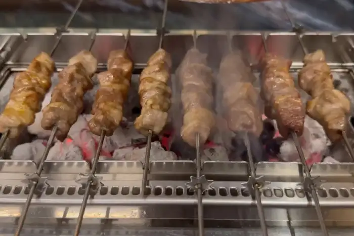 숯불 위에서 노릇하게 구워지는 양꼬치 꼬치들