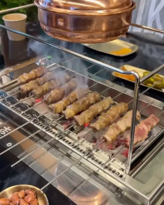 자동 꼬치 구이기 위에서 익어가는 여러 개의 양꼬치
