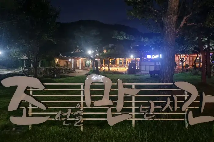 밤에 조명이 켜진 카페의 외부 전경. '조용한 시간을 선물하는 한옥카페'라는 간판이 보인다.