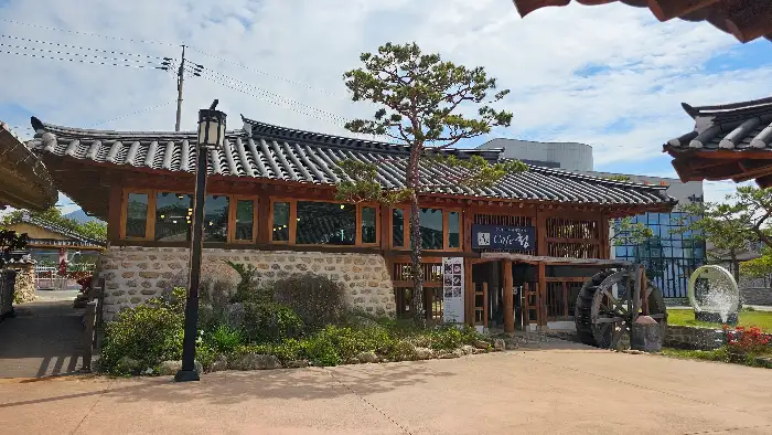 카페 외관의 모습. 넓은 마당과 나무, 그리고 한옥 건물이 보인다.