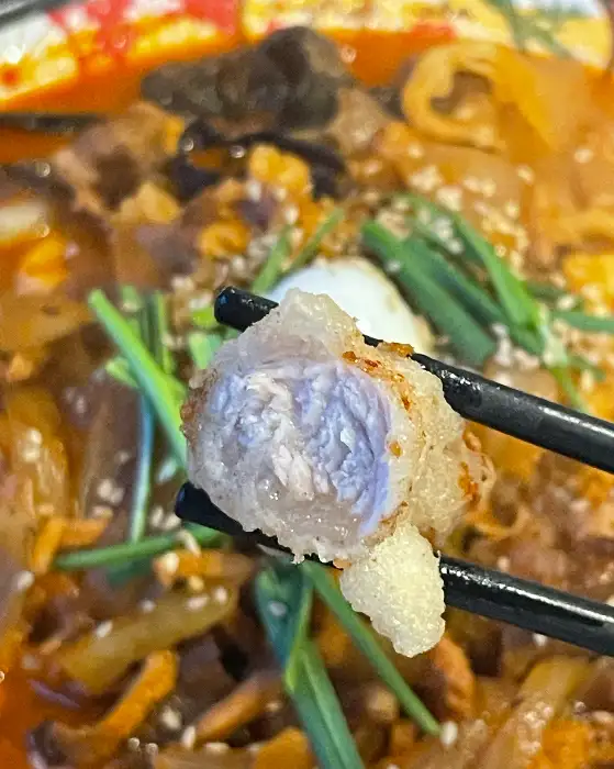 탕수육 한 점을 집게로 집어 올린 모습