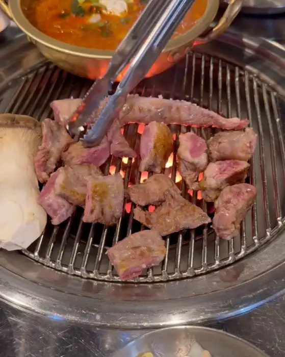 집게로 고기를 뒤집는 손길이 분주합니다. 연탄불 위에서 노릇하게 익어가는 고기들이 맛있어 보입니다.