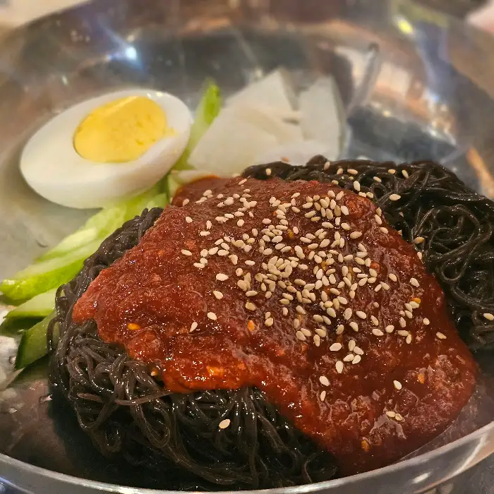 새빨간 양념과 함께 검은색 면발이 돋보이는 냉면. 시원하게 후식으로 즐기기 좋을 것 같습니다.
