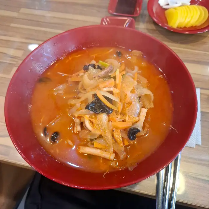 짬뽕 국물의 클로즈업 사진, 다양한 건더기가 보인다.