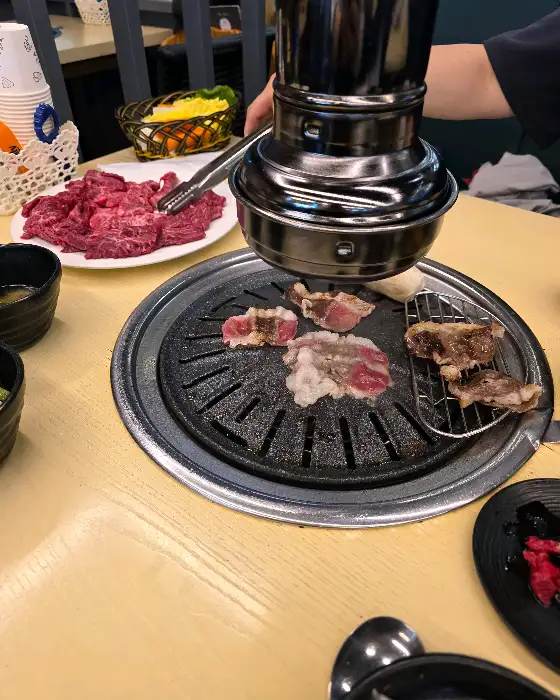 테이블 위에서 구워지고 있는 고기와 숯불