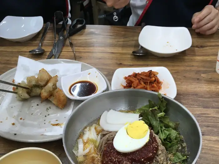 테이블 위에 놓인 막국수, 감자전, 김치 등의 음식들