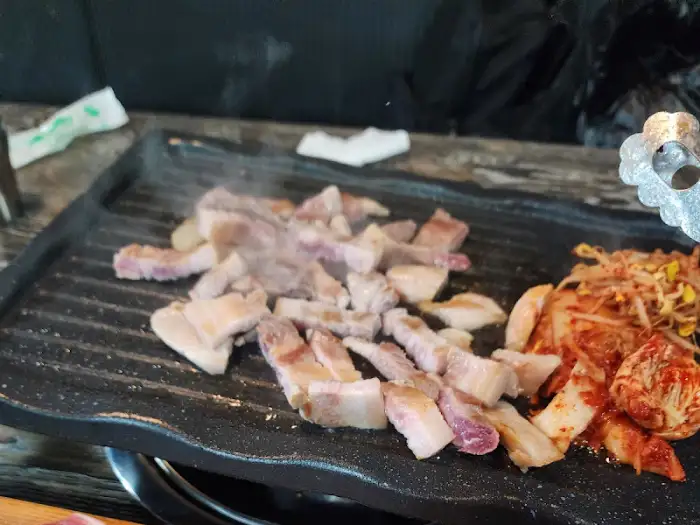 불판 위에서 삼겹살 조각들이 노릇하게 익고 있습니다.