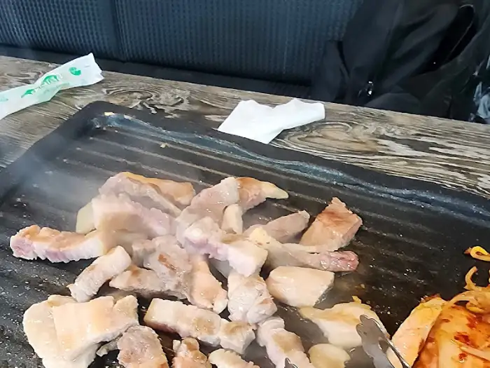 불판 위에서 익어가는 삼겹살 조각들이 김을 내뿜고 있습니다.