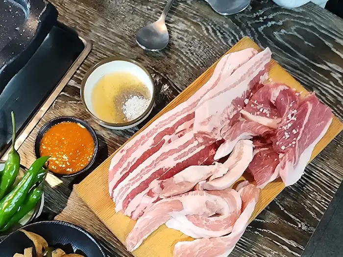 주문한 삼겹살과 곁들임 메뉴, 그리고 소스가 준비되어 있습니다.