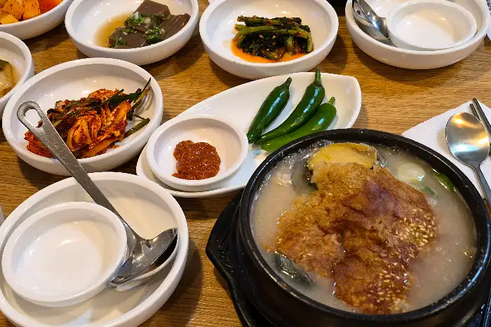 테이블 위에 차려진 여러 반찬과 삼계탕 사진