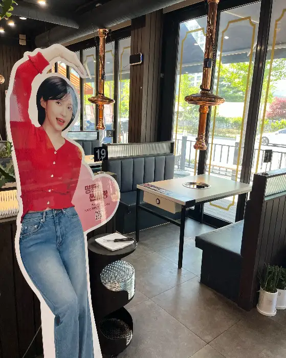 식당 내부 입구 모습. 귀여운 캐릭터 입간판이 세워져 있고, 넓은 홀이 보인다.