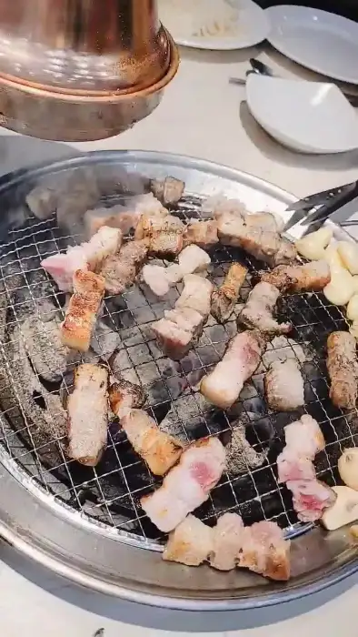 다양하게 구워진 고기 조각들과 마늘이 숯불 위에 놓여 있다.