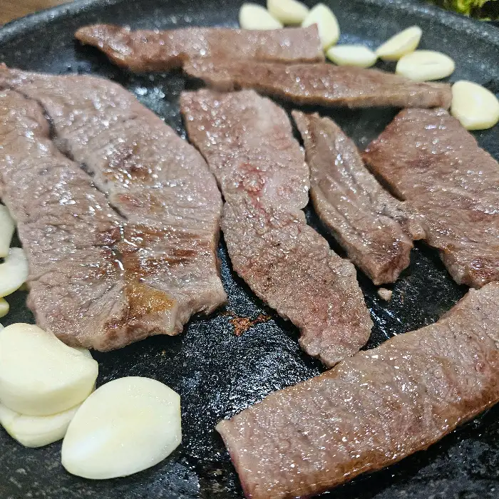 석쇠 위에서 익어가는 다양한 부위의 소고기와 마늘