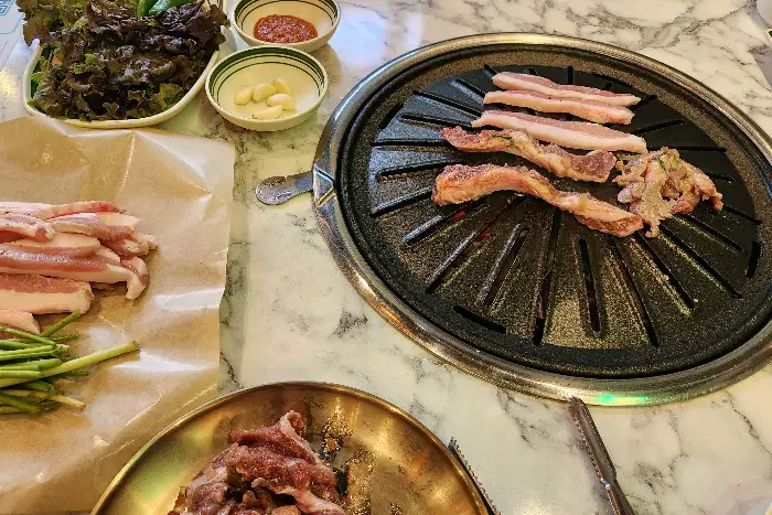 숯불 위에 구워지는 삼겹살과 곁들임 메뉴