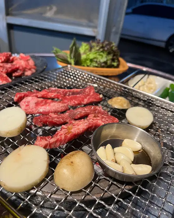 숯불 위에 놓인 신선한 갈비살과 감자, 마늘