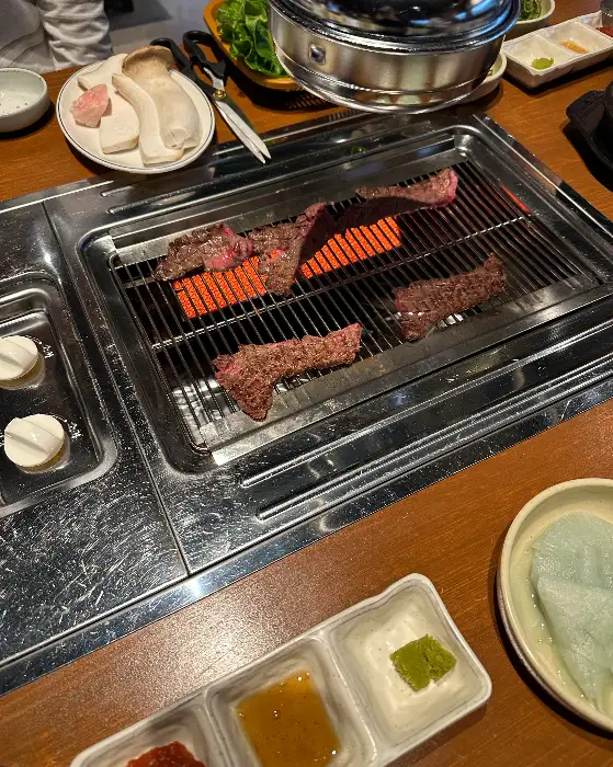집게로 집은 잘 구워진 소고기 한 점