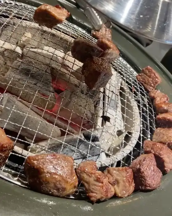 화로구이 위에서 숯불에 구워지고 있는 다양한 부위의 소고기 조각들