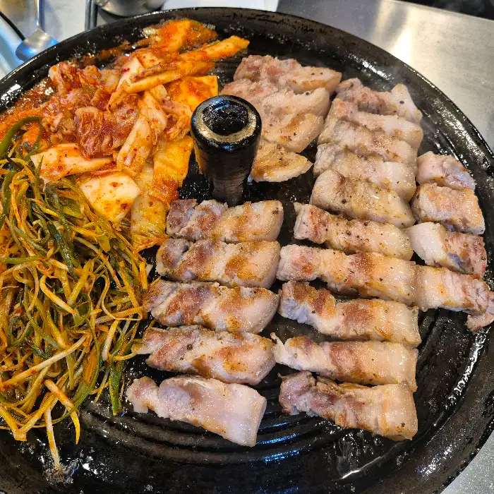 두툼하게 썰려 나온 미박삼겹살과 갓김치, 파절이가 함께 불판 위에 올라간 모습