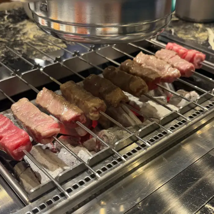 신선해 보이는 양꼬치 여러 꼬치가 숯불 그릴 위에서 익고 있는 모습
