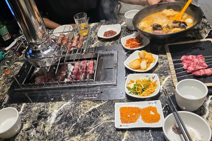 테이블에 차려진 다양한 음식들, 양꼬치, 마라탕, 곁들임 반찬 등