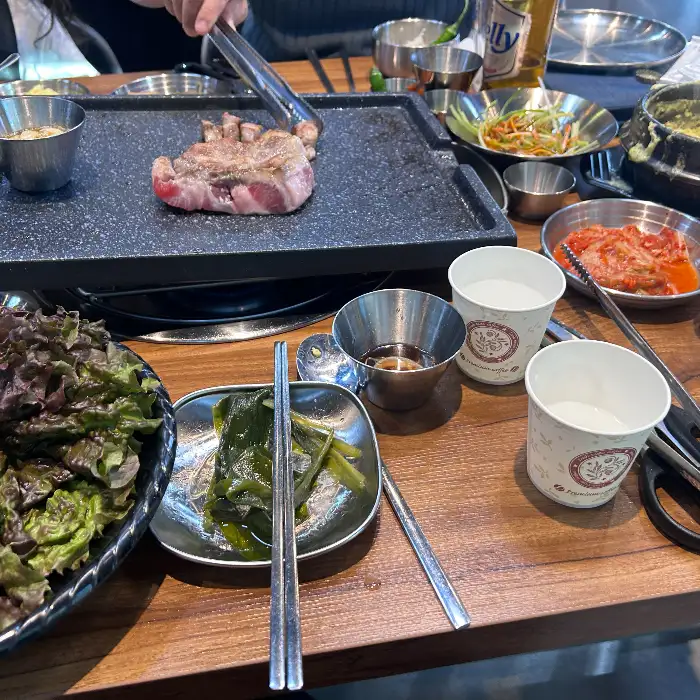 상추쌈에 고기와 쌈 채소, 마늘 등을 얹어 싸는 모습