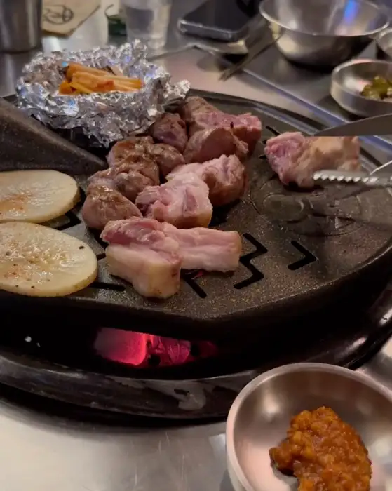 불판 위에서 익어가는 고기와 곁들임 메뉴