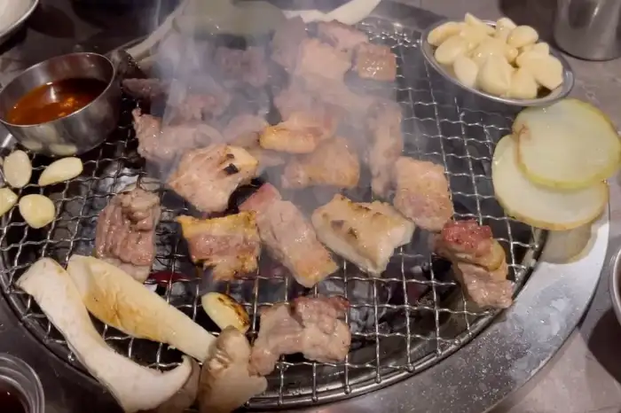 다양한 부위의 고기가 숯불 위에서 익어가며 맛있는 연기를 내뿜고 있는 모습