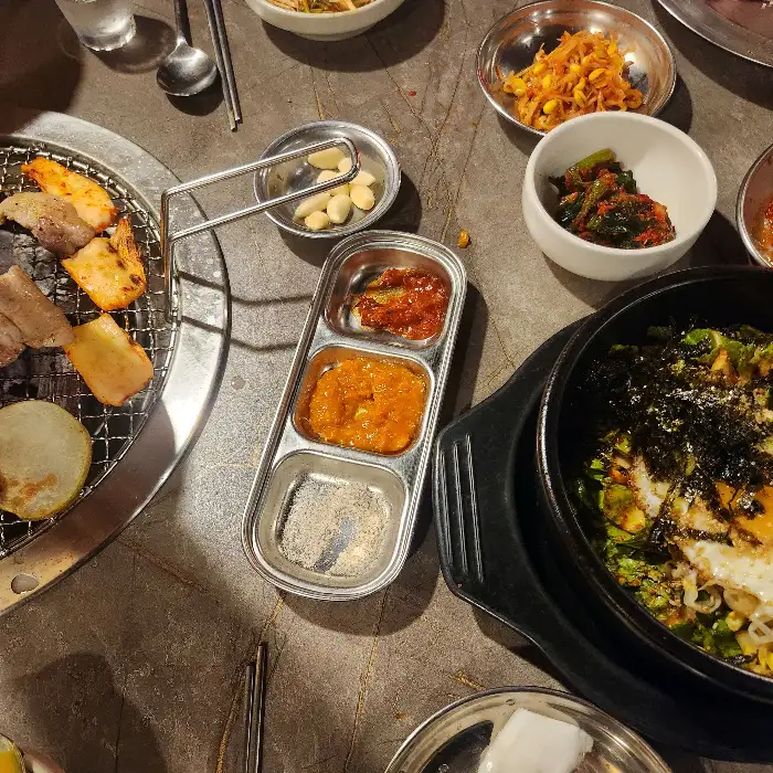 다양한 소스와 밑반찬, 그리고 갓 구워진 고기가 함께 놓인 테이블 모습