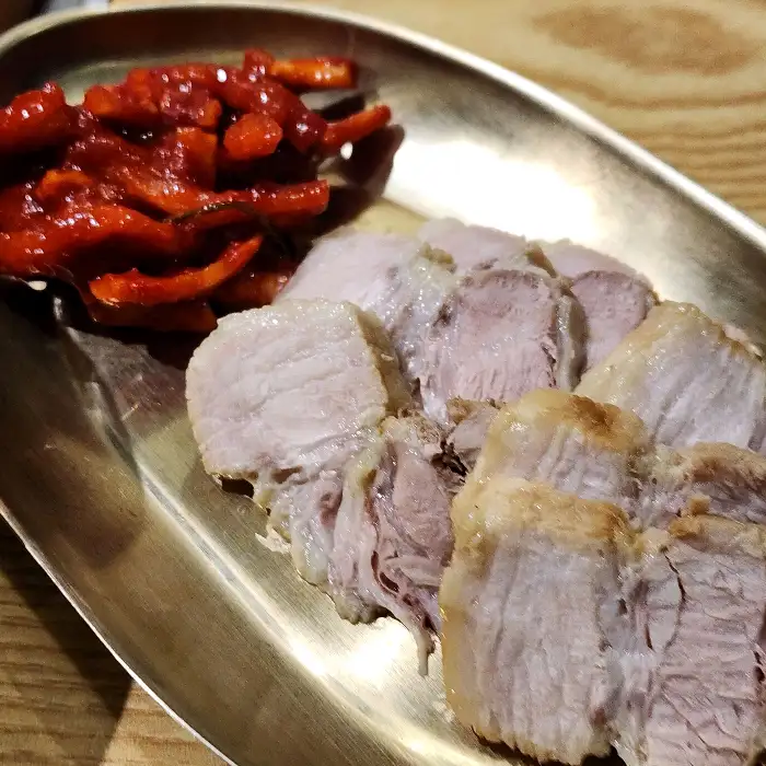 푸짐하게 담긴 수육 한 점과 새빨간 양념의 깍두기.
