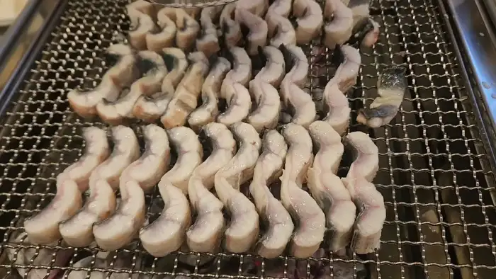 초벌되지 않은 신선한 장어 조각들이 불판 위에 가지런히 놓여 있습니다.
