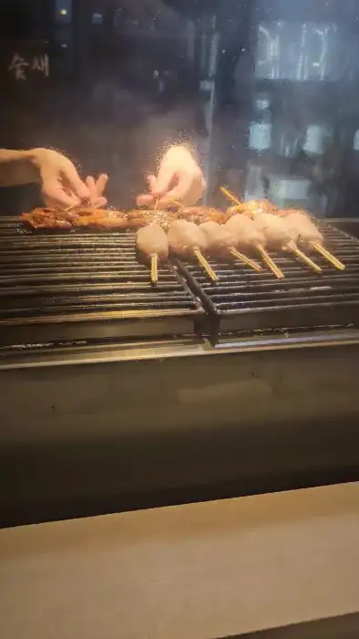 숯불 위에서 여러 종류의 꼬치가 구워지고 있는 모습
