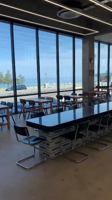 넓은 통유리창 너머로 보이는 바다 풍경과 테이블 좌석