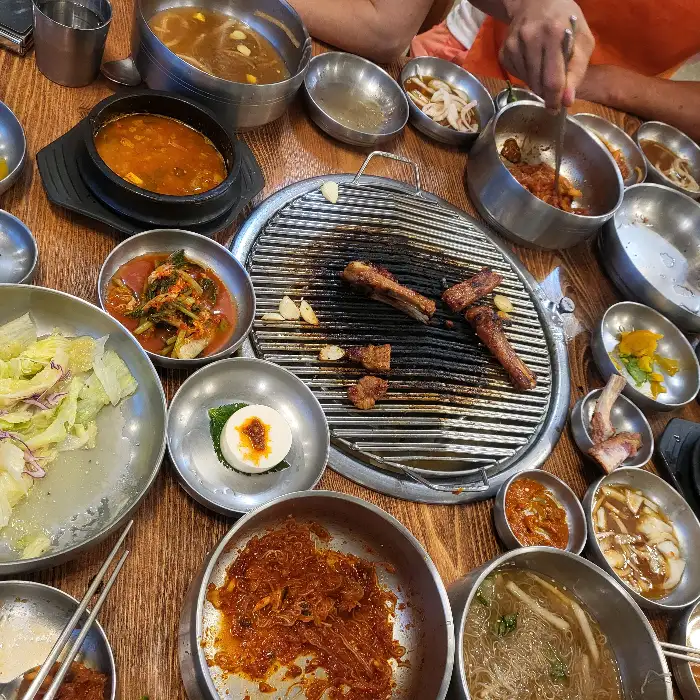 숯불 위에 구워지고 있는 맛있는 갈비와 다양한 반찬들
