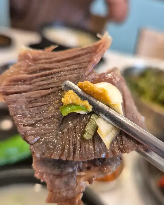 곰탕 고기 한 점을 젓가락으로 집어 올린 모습