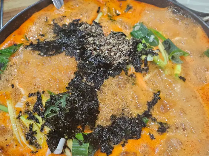 칼국수 국물 위에 김가루와 파가 뿌려져 있는 모습. 볶음밥을 준비하는 단계로 보인다.