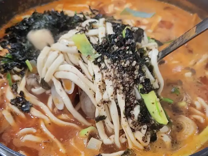 면발에 국물과 해물이 듬뿍 묻어 있는 칼국수 클로즈업 사진.
