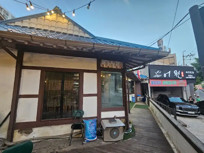 식당의 옆모습. 전통적인 한옥 스타일의 건물과 튀어나온 유리창, 나무로 된 문틀이 보인다. 간이 의자와 에어컨 실외기가 놓여 있다.