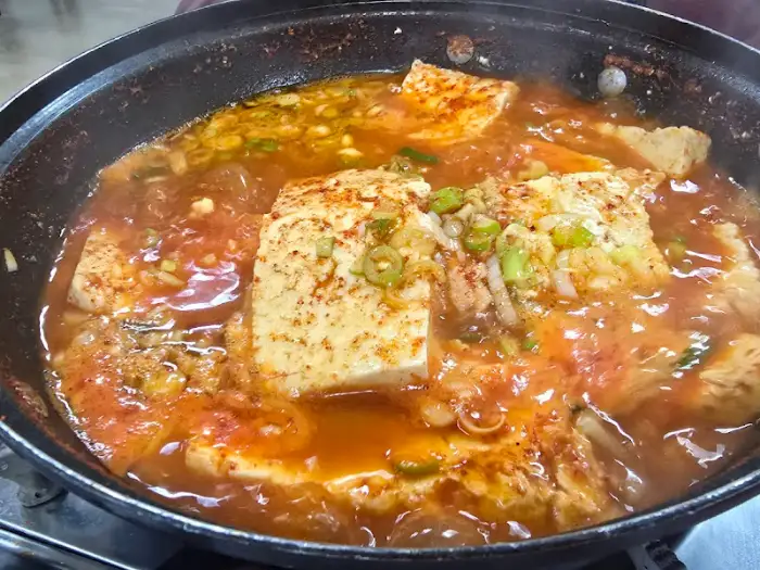 뚝배기에 담긴 두부짜글이가 보글보글 끓고 있습니다. 큼직한 두부 조각들과 국물이 먹음직스럽습니다.