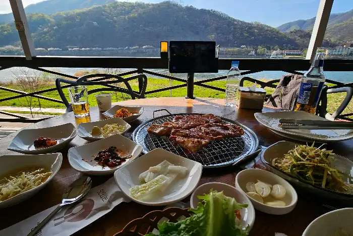 테이블에 차려진 푸짐한 돼지갈비와 밑반찬, 그리고 멋진 북한강 뷰가 보이는 풍경