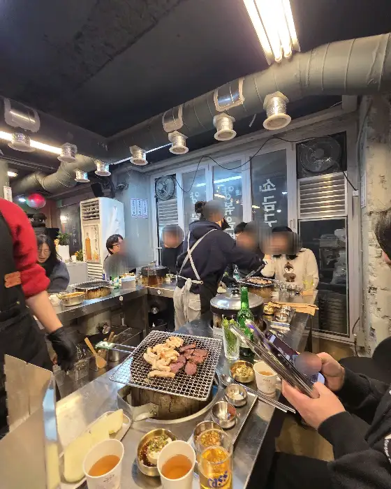 연신내 형제곱창 내부 모습, 연탄불 앞에 사람들이 둘러앉아 있다.