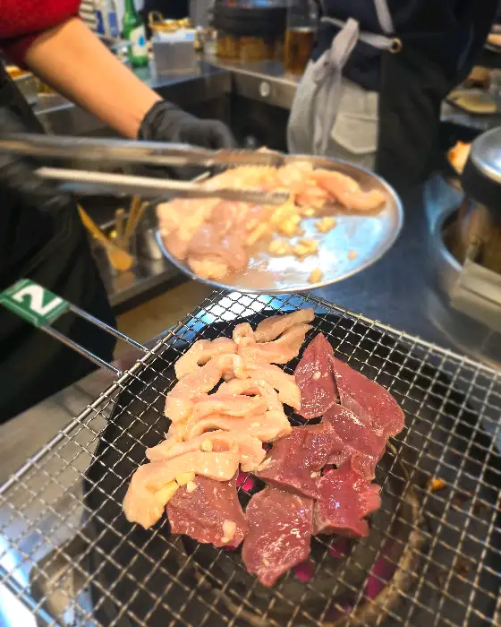 직원이 곱창과 염통을 연탄불에 올리고 있는 모습.
