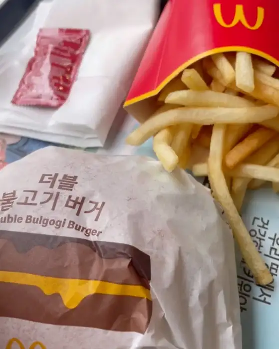 더블 불고기 버거와 케첩, 감자튀김이 놓여 있는 모습